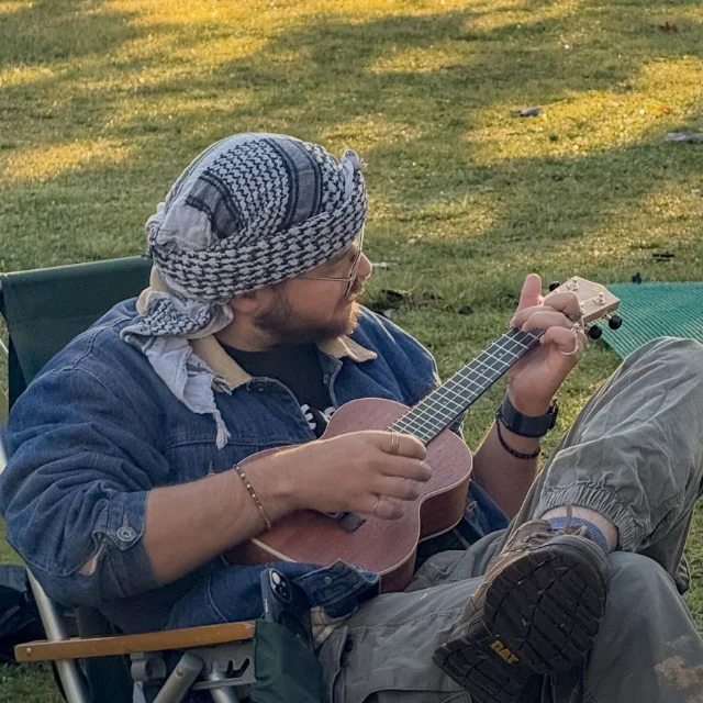 Lauwrens Reyneke playing a ukulele at a campsite